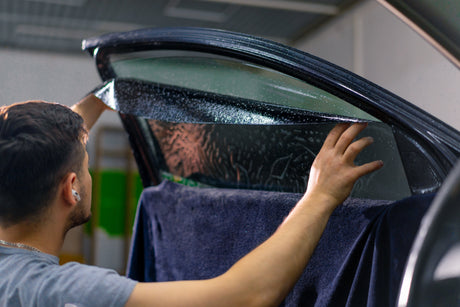 Man applying window tint vinyl to vehicle window