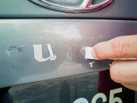Man removing adhesive leftover from vinyl graphics on vehicle