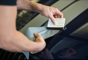 Man applying vinyl to vehicle with squeegee