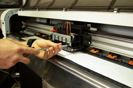 Man using a screw driver to access a vinyl cutter blade carriage