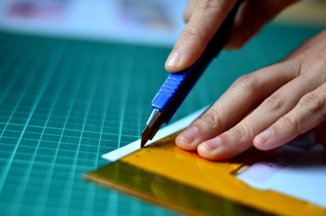 Man using a cutting took and ruler on cutting mat to make precise cuts to vinyl